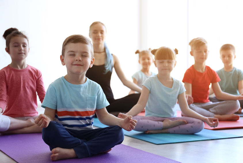 Little children and their teacher practicing yoga in gym &copy;