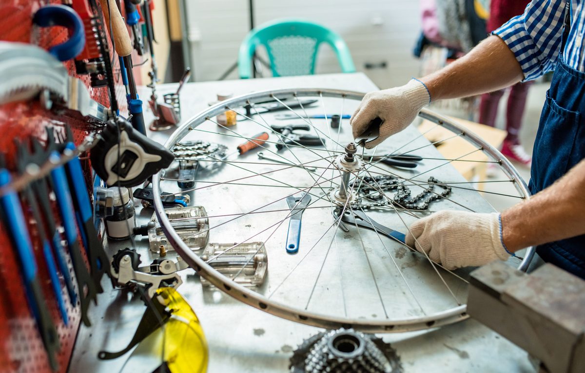 Gloved hands of repairing master tightening bolts on wheel by workplace ©